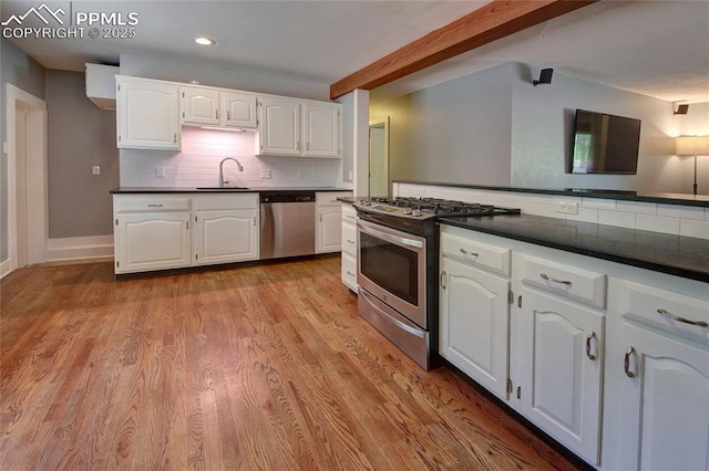 1018 Saturn Dr, Colorado Springs, CO 80905 - kitchen featuring stainless steel appliances, dark countertops, white cabinets, tasteful backsplash, and light wood finished floors