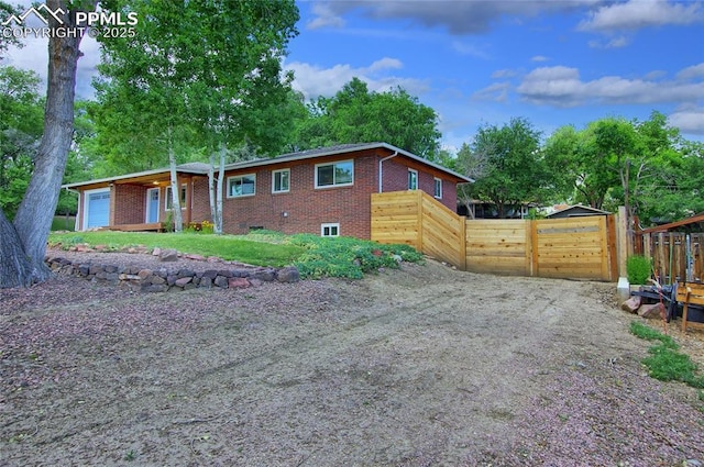 1018 Saturn Dr, Colorado Springs, CO 80905 - view of front of house featuring brick siding, a garage, and dirt driveway