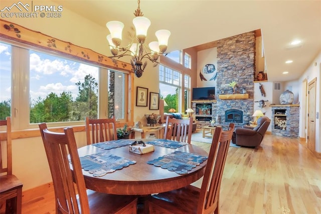 71 Crestone Cir, Florissant, CO 80816 - dining space with a stone fireplace, light wood-style floors, a chandelier, and a towering ceiling