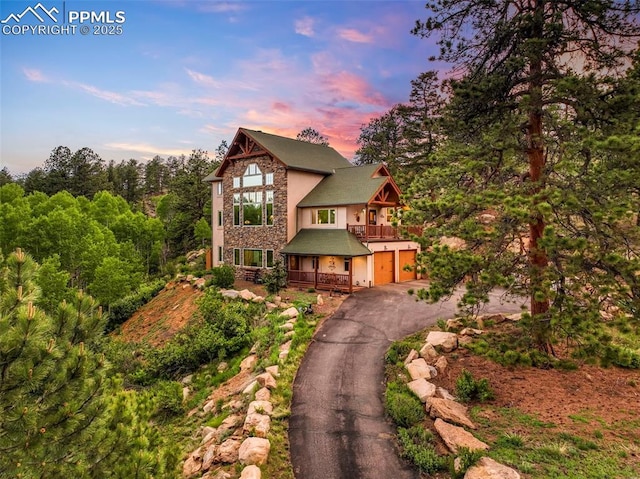 71 Crestone Cir, Florissant, CO 80816 - view of front of property featuring a balcony, an attached garage, driveway, stucco siding, and stone siding