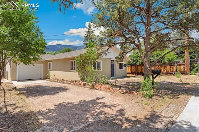 121 Via, San Miguel, Manitou Springs, CO 80829 - view of front of property with dirt driveway, a garage, stucco siding, and a mountain view