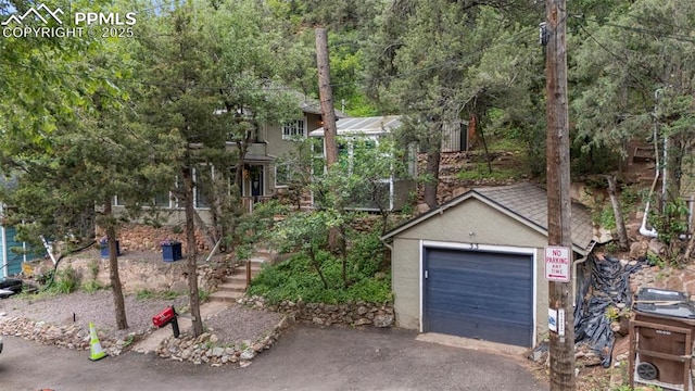 33 Minnehaha Ave, Manitou Springs, CO 80829 - view of property hidden behind natural elements with driveway, a garage, and stucco siding