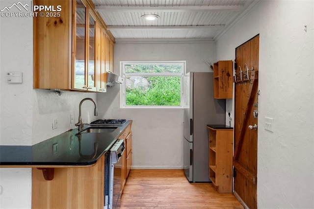 33 Minnehaha Ave, Manitou Springs, CO 80829 - kitchen featuring light wood-type flooring, dark countertops, brown cabinets, freestanding refrigerator, and beam ceiling