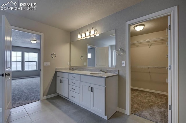 8235 Kittrick Pl, Falcon, CO 80831 - bathroom with double vanity, a textured ceiling, tile patterned flooring, and a walk in closet