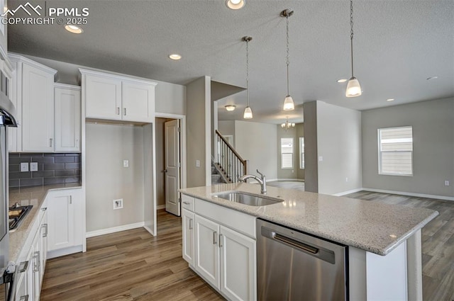 8235 Kittrick Pl, Falcon, CO 80831 - kitchen with appliances with stainless steel finishes, open floor plan, white cabinetry, wood finished floors, and recessed lighting