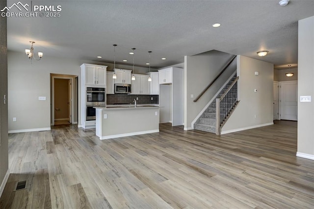 8235 Kittrick Pl, Falcon, CO 80831 - kitchen featuring stainless steel appliances, open floor plan, white cabinets, tasteful backsplash, and recessed lighting