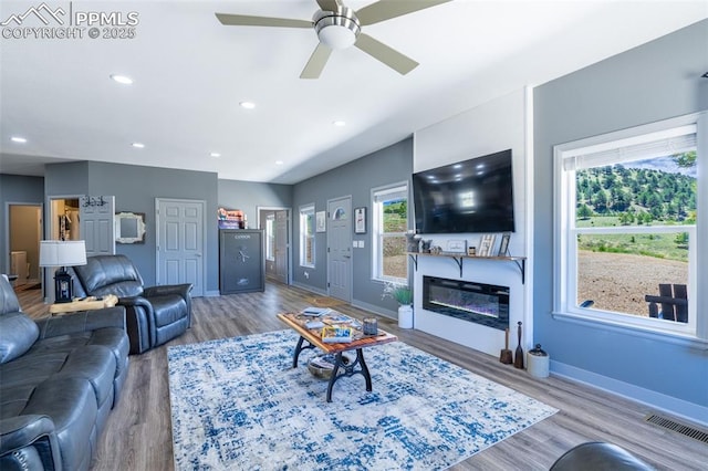 333 Della Fox Ln, Westcliffe, CO 81252 - living area featuring wood finished floors, a ceiling fan, a glass covered fireplace, and recessed lighting