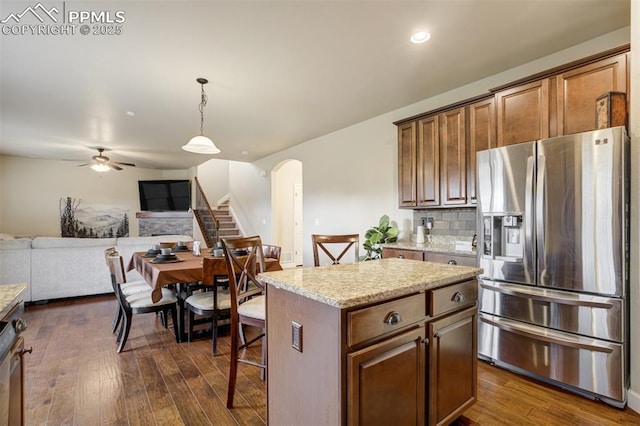 10280 Abrams Dr, Colorado Springs, CO 80925 - kitchen with stainless steel fridge, open floor plan, arched walkways, dark wood-style floors, and a ceiling fan