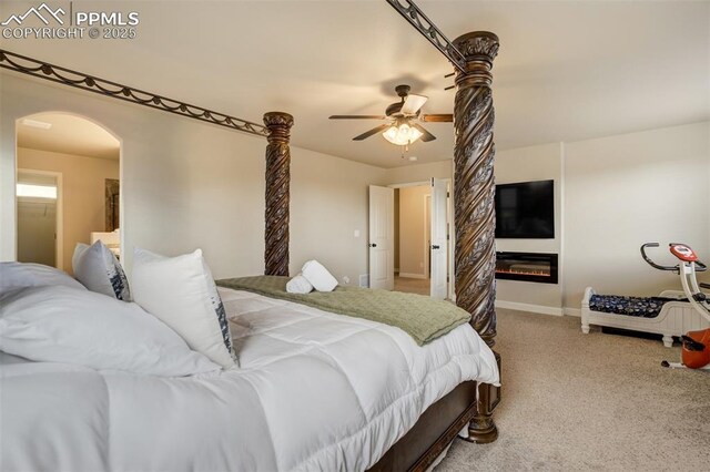 10280 Abrams Dr, Colorado Springs, CO 80925 - carpeted bedroom featuring arched walkways, a glass covered fireplace, and ceiling fan