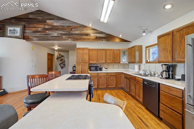 2550 Slocum Rd, Peyton, CO 80831 - kitchen with stainless steel appliances, lofted ceiling, a kitchen bar, light wood-style flooring, and light countertops