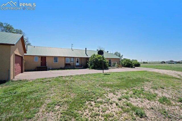 2550 Slocum Rd, Peyton, CO 80831 - ranch-style home featuring a metal roof, a front lawn, driveway, and stucco siding