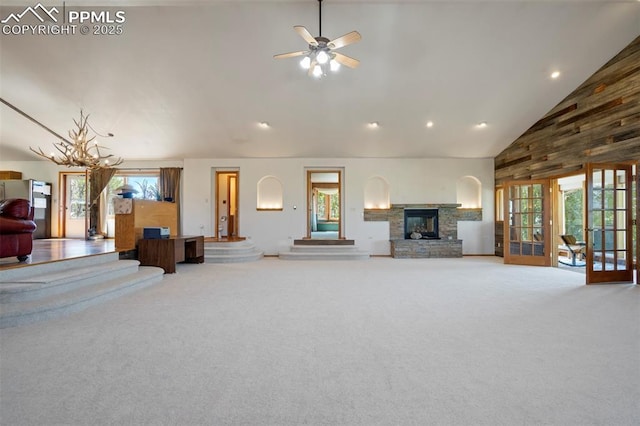 2550 Slocum Rd, Peyton, CO 80831 - unfurnished living room featuring carpet, high vaulted ceiling, a fireplace, a ceiling fan, and wooden walls