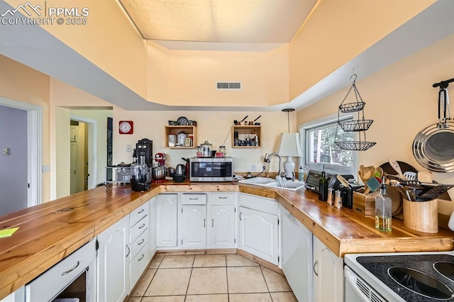 376 Gardenia Rd, Woodland Park, CO 80863 - kitchen with white appliances, wood counters, light tile patterned floors, white cabinets, and a peninsula