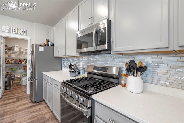 8101 Goldenray Pl, Colorado Springs, CO 80908 - kitchen with appliances with stainless steel finishes, tasteful backsplash, and light wood-style flooring