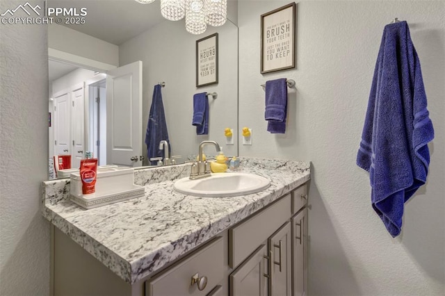 8101 Goldenray Pl, Colorado Springs, CO 80908 - bathroom with vanity, a textured wall, and a chandelier