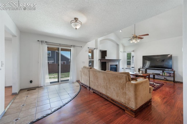 9503 Brisk Breeze Ct, Colorado Springs, CO 80925 - living room with a ceiling fan, a textured ceiling, lofted ceiling, wood finished floors, and a fireplace