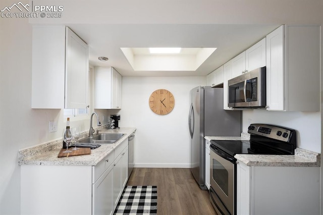 1363 Soaring Eagle Dr, Colorado Springs, CO 80915 - kitchen with stainless steel appliances, a raised ceiling, white cabinetry, wood finished floors, and light countertops