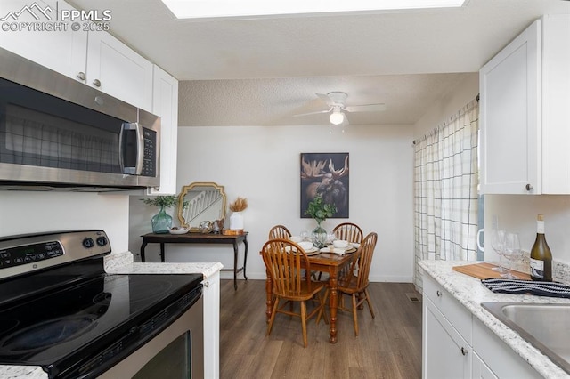 1363 Soaring Eagle Dr, Colorado Springs, CO 80915 - kitchen featuring appliances with stainless steel finishes, wood finished floors, white cabinetry, and a ceiling fan