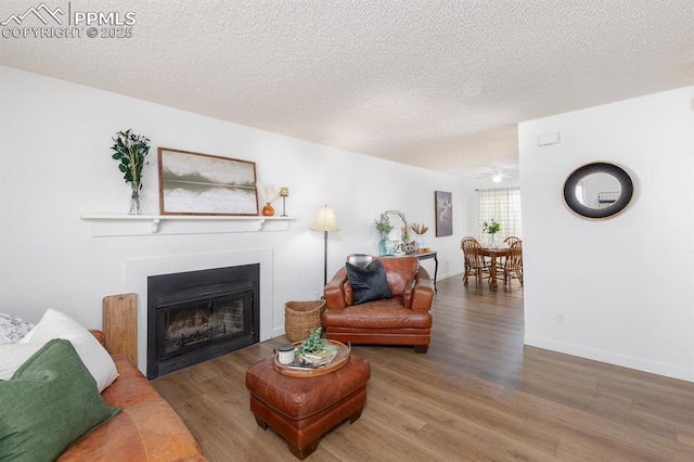 1363 Soaring Eagle Dr, Colorado Springs, CO 80915 - living area with wood finished floors, a tile fireplace, ceiling fan, and a textured ceiling