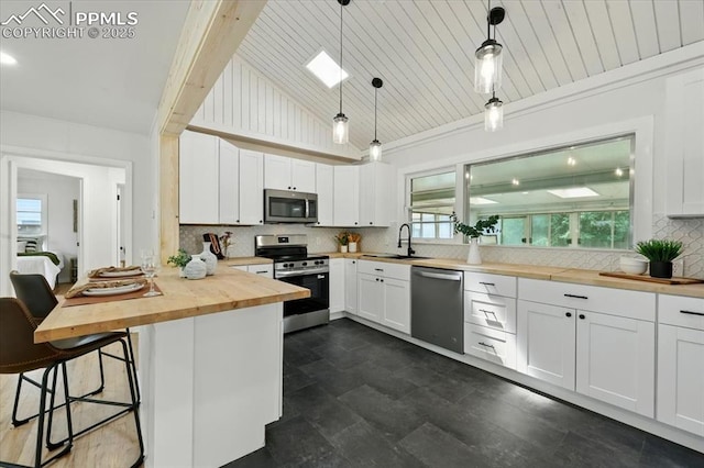 1314 Pioneer Rd, Colorado Springs, CO 80907 - kitchen featuring appliances with stainless steel finishes, wooden counters, a kitchen breakfast bar, tasteful backsplash, and lofted ceiling