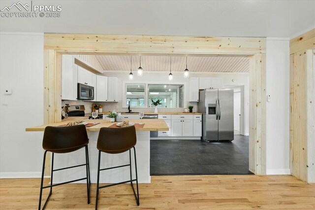 1314 Pioneer Rd, Colorado Springs, CO 80907 - kitchen with stainless steel appliances, a peninsula, butcher block counters, light wood-type flooring, and white cabinetry