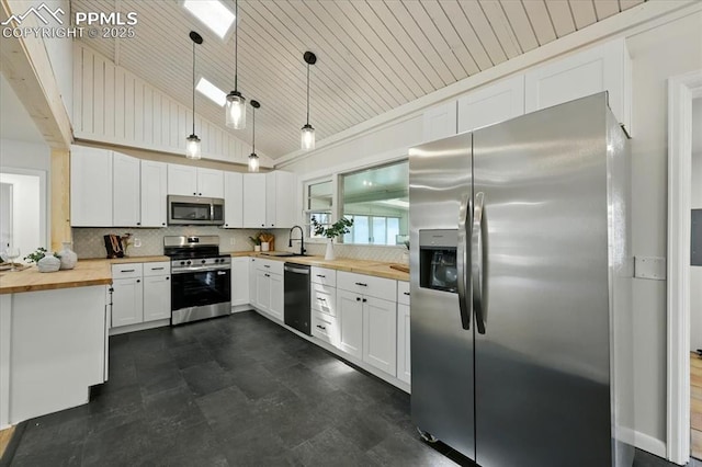 1314 Pioneer Rd, Colorado Springs, CO 80907 - kitchen featuring butcher block countertops, appliances with stainless steel finishes, vaulted ceiling, hanging light fixtures, and decorative backsplash