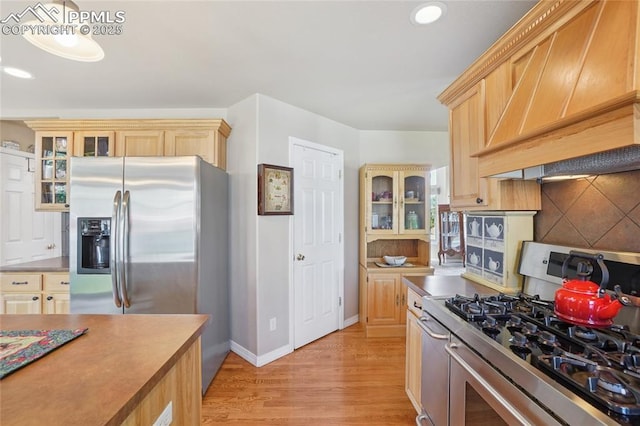 392 Pyrite Ter, Colorado Springs, CO 80905 - kitchen featuring stainless steel appliances, premium range hood, light wood-style flooring, decorative backsplash, and glass insert cabinets