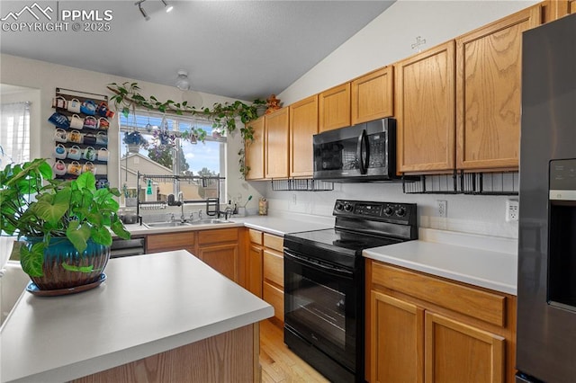6355 Casual Dr, Colorado Springs, CO 80923 - kitchen featuring black appliances, lofted ceiling, light countertops, and light wood-style floors