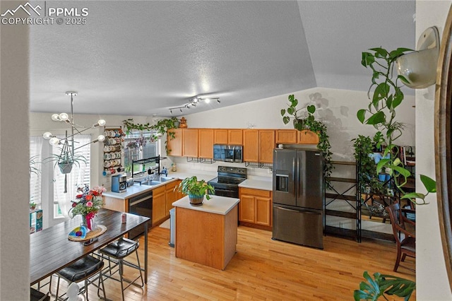6355 Casual Dr, Colorado Springs, CO 80923 - kitchen featuring black appliances, light countertops, a center island, light wood-type flooring, and lofted ceiling