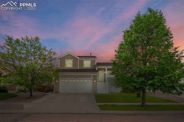 6355 Casual Dr, Colorado Springs, CO 80923 - tri-level home with concrete driveway, an attached garage, stone siding, and a lawn