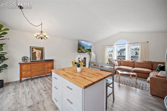 7735 Lindsey Dr, Colorado Springs, CO 80920 - kitchen featuring vaulted ceiling, a breakfast bar area, wooden counters, a glass covered fireplace, and a chandelier