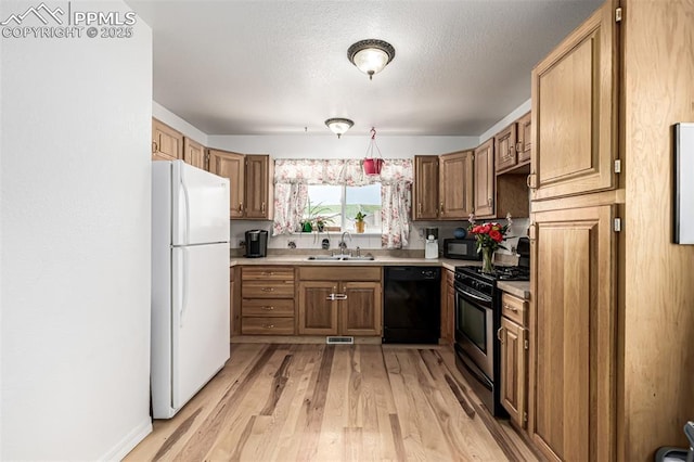 1013 Maxwell St, Colorado Springs, CO 80906 - kitchen with black appliances, light countertops, light wood-style floors, brown cabinets, and a textured ceiling