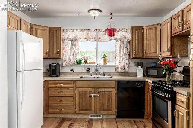 1013 Maxwell St, Colorado Springs, CO 80906 - kitchen featuring black appliances, light countertops, tasteful backsplash, and light wood-style floors