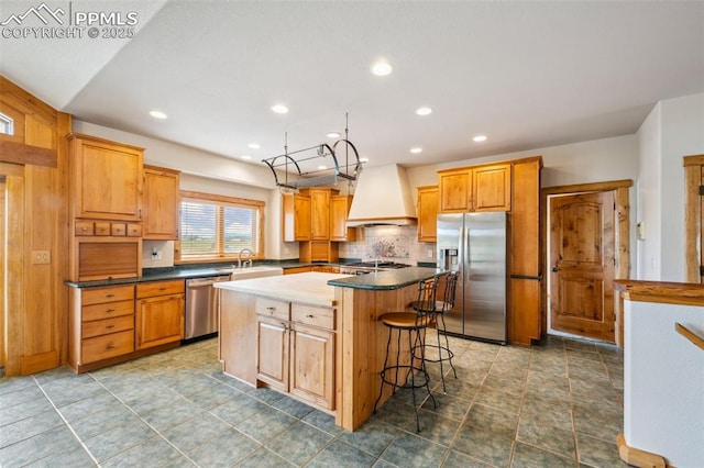 16575 Dancing Wolf Way, Colorado Springs, CO 80908 - kitchen featuring appliances with stainless steel finishes, premium range hood, a kitchen island, dark countertops, and decorative backsplash