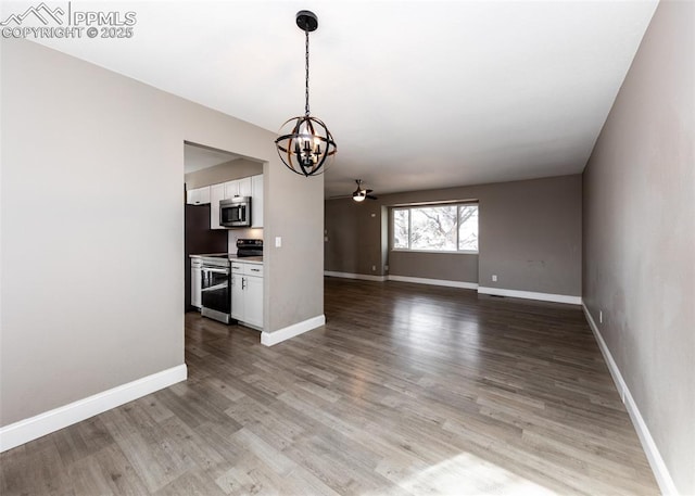 7465 Painted Rock Dr, Colorado Springs, CO 80911 - unfurnished living room featuring a chandelier, a ceiling fan, and light wood-style floors