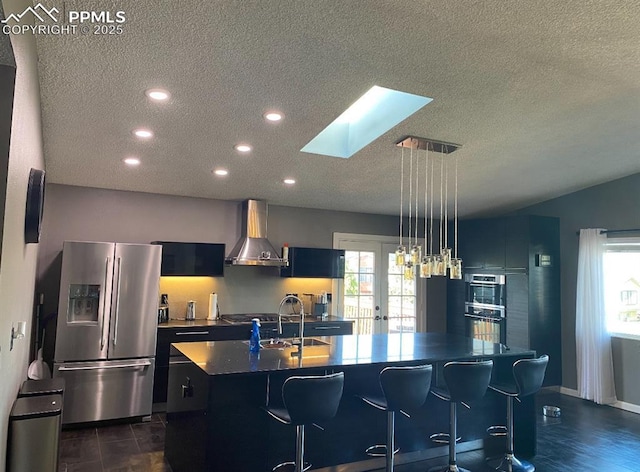 4110 Novia Dr, Colorado Springs, CO 80911 - kitchen with appliances with stainless steel finishes, wall chimney range hood, a textured ceiling, a skylight, and an island with sink