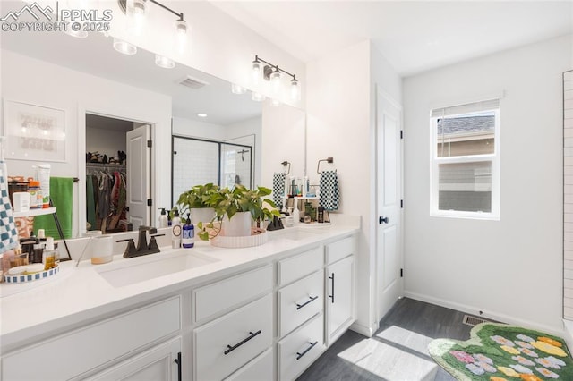 16423 Mountain Flax Dr, Monument, CO 80132 - full bath with double vanity, a shower stall, a spacious closet, and wood finished floors