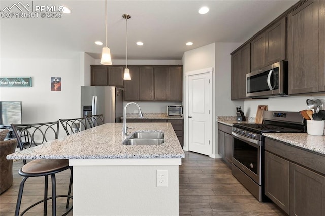 2481 Horsemanship Ct, Colorado Springs, CO 80922 - kitchen with appliances with stainless steel finishes, dark brown cabinets, dark wood-type flooring, a breakfast bar area, and recessed lighting