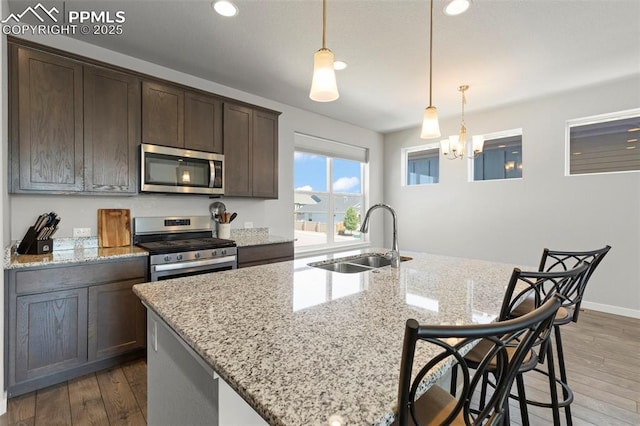 2481 Horsemanship Ct, Colorado Springs, CO 80922 - kitchen with stainless steel appliances, dark brown cabinetry, wood finished floors, an island with sink, and recessed lighting