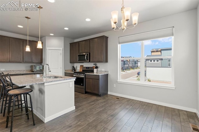 2481 Horsemanship Ct, Colorado Springs, CO 80922 - kitchen with stainless steel appliances, dark brown cabinetry, recessed lighting, dark wood-style floors, and an island with sink