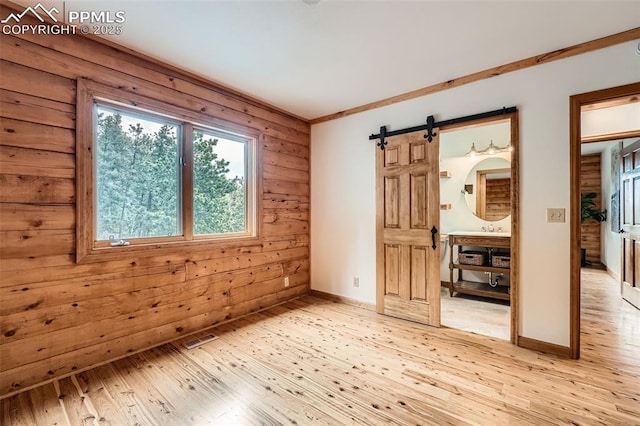 1527 S Pine Dr, Bailey, CO 80421 - unfurnished room featuring a barn door, light wood finished floors, and wood walls