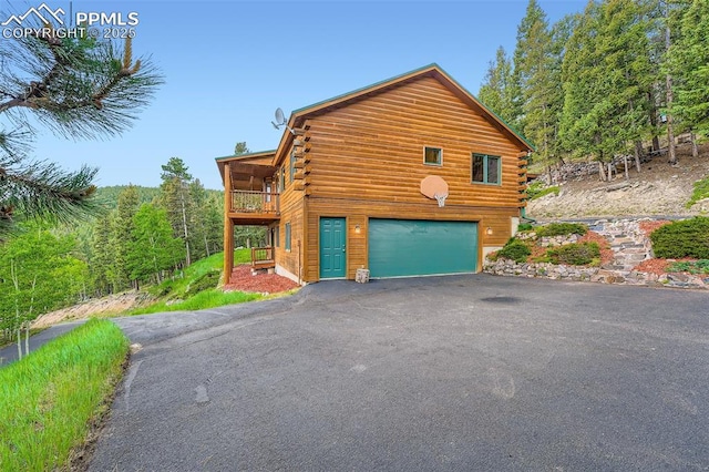 1527 S Pine Dr, Bailey, CO 80421 - view of side of home with asphalt driveway, log siding, an attached garage, and a balcony