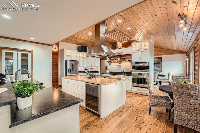1527 S Pine Dr, Bailey, CO 80421 - kitchen featuring wine cooler, island exhaust hood, appliances with stainless steel finishes, vaulted ceiling, and a kitchen island