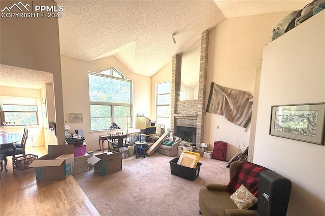 945 Marlstone Pl, Colorado Springs, CO 80904 - living room featuring plenty of natural light, a textured ceiling, a fireplace, wood finished floors, and high vaulted ceiling