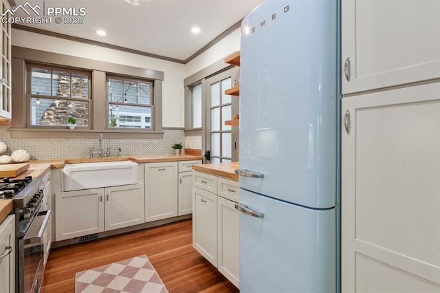 1401 N Tejon St, Colorado Springs, CO 80907 - kitchen with freestanding refrigerator, wood counters, high end stainless steel range oven, decorative backsplash, and ornamental molding