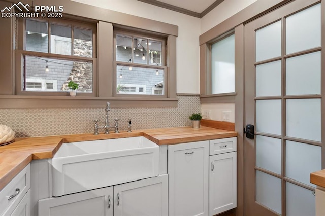 1401 N Tejon St, Colorado Springs, CO 80907 - kitchen featuring butcher block counters, decorative backsplash, crown molding, and white cabinetry