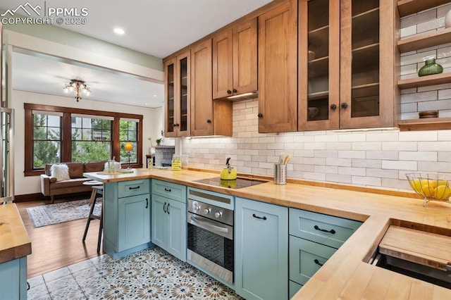1401 N Tejon St, Colorado Springs, CO 80907 - kitchen with wood counters, stainless steel oven, black electric cooktop, open floor plan, and glass insert cabinets