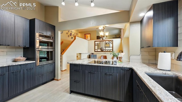 440 Torrey Pines Way, Colorado Springs, CO 80921 - kitchen featuring black electric stovetop, stainless steel double oven, decorative backsplash, light wood-style flooring, and a peninsula