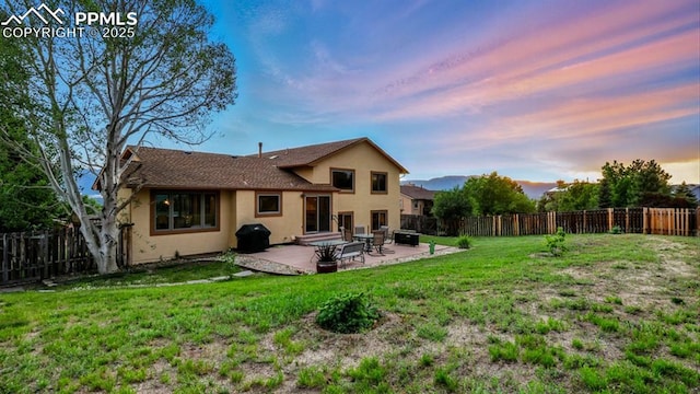 440 Torrey Pines Way, Colorado Springs, CO 80921 - back of house at dusk featuring stucco siding, a fenced backyard, a patio, and a shingled roof