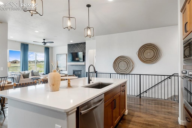 9996 Antelope Ravine Dr, Colorado Springs, CO 80908 - kitchen featuring stainless steel appliances, open floor plan, dark wood-style flooring, brown cabinets, and a fireplace